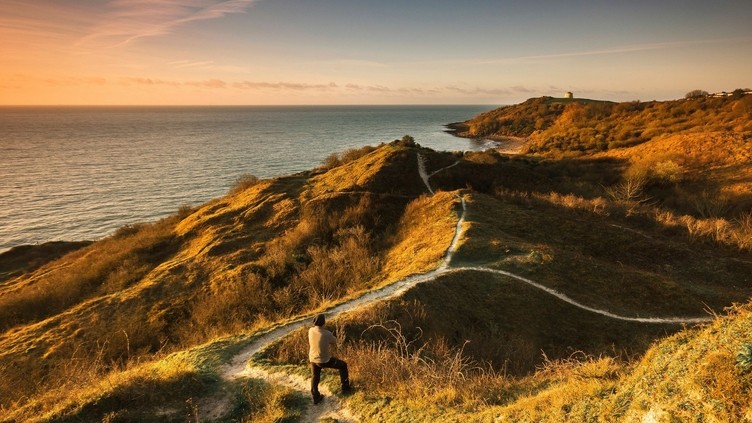Man standing on coastal path with view of path ahead